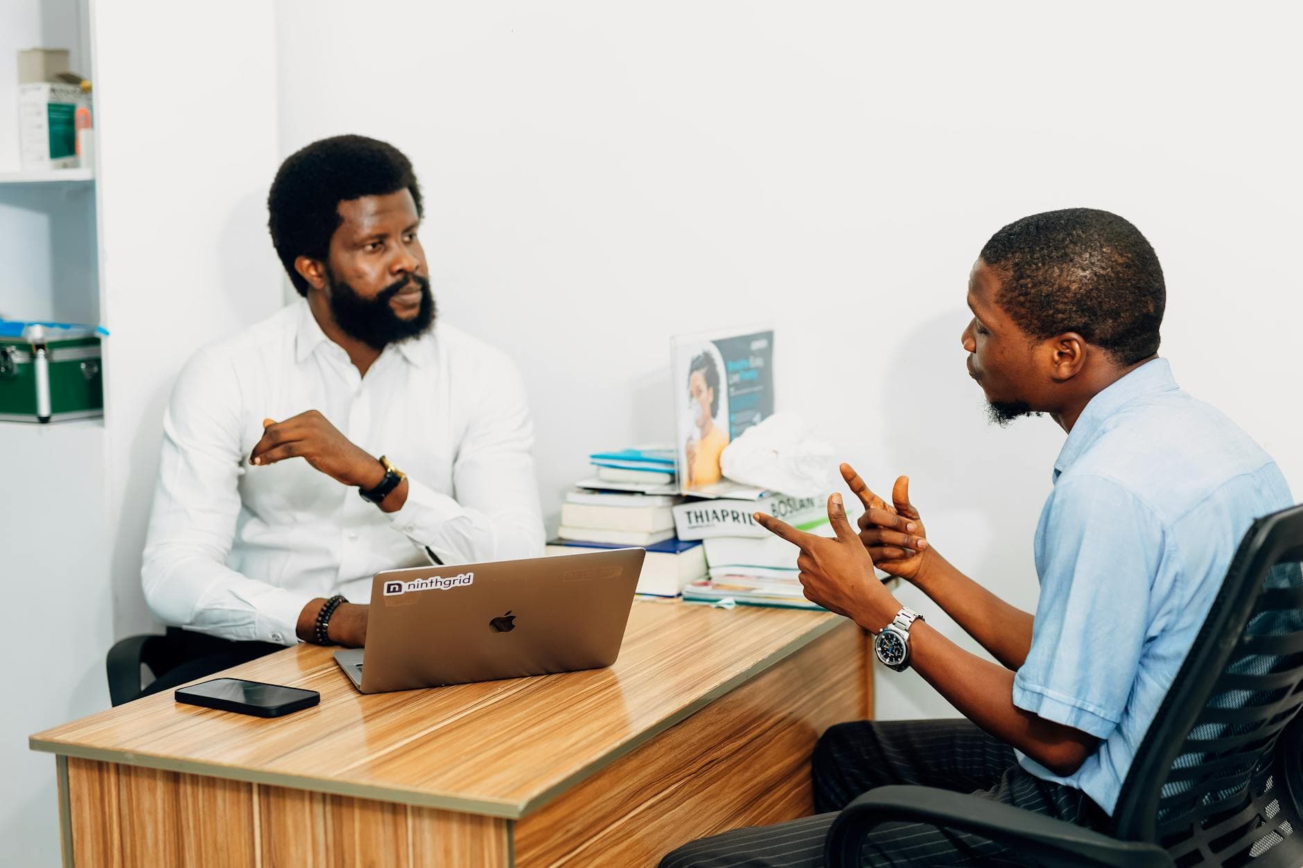 Two real estate professionals in conversation at a Nashville office workspace — collaboration between agents