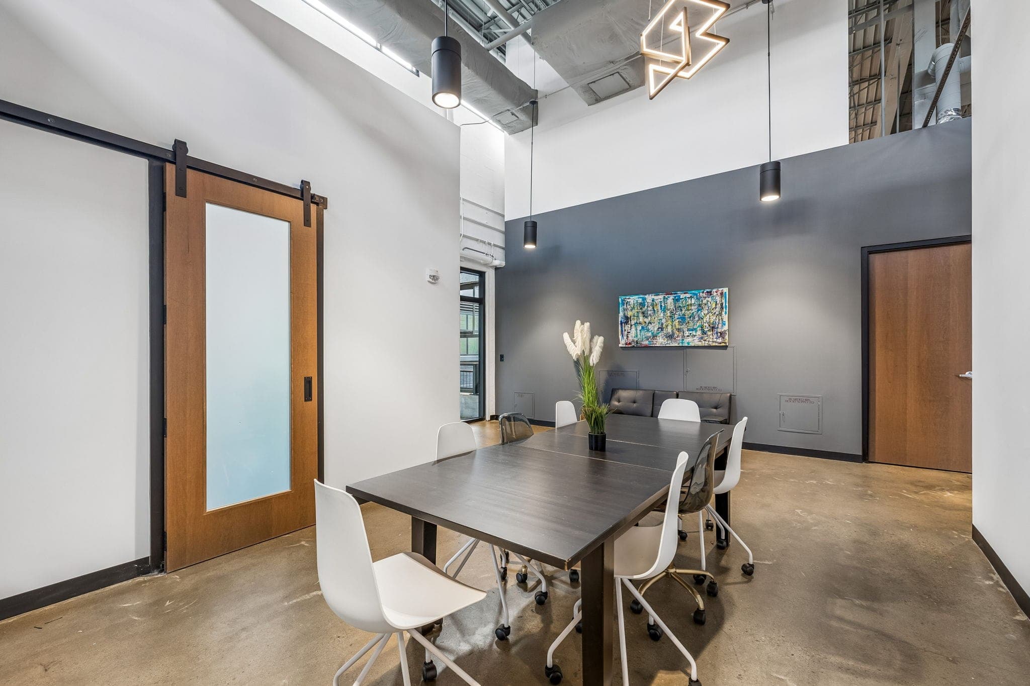 Meeting nook with mixed seating, navy accent wall, and a barn door at the Nashville office